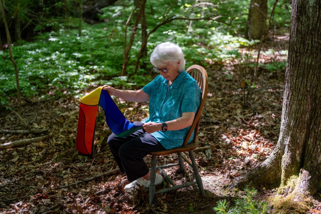 Rev. Carter Heyward sits on a chair outside her home.