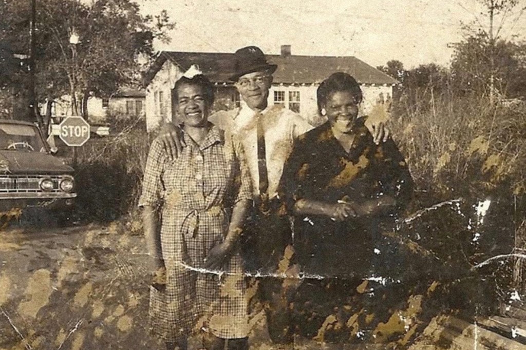 A yellowing printed photograph of three Black people smiling at the camera.