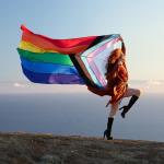 Pattie Gonia holds a Pride Progress Flag.