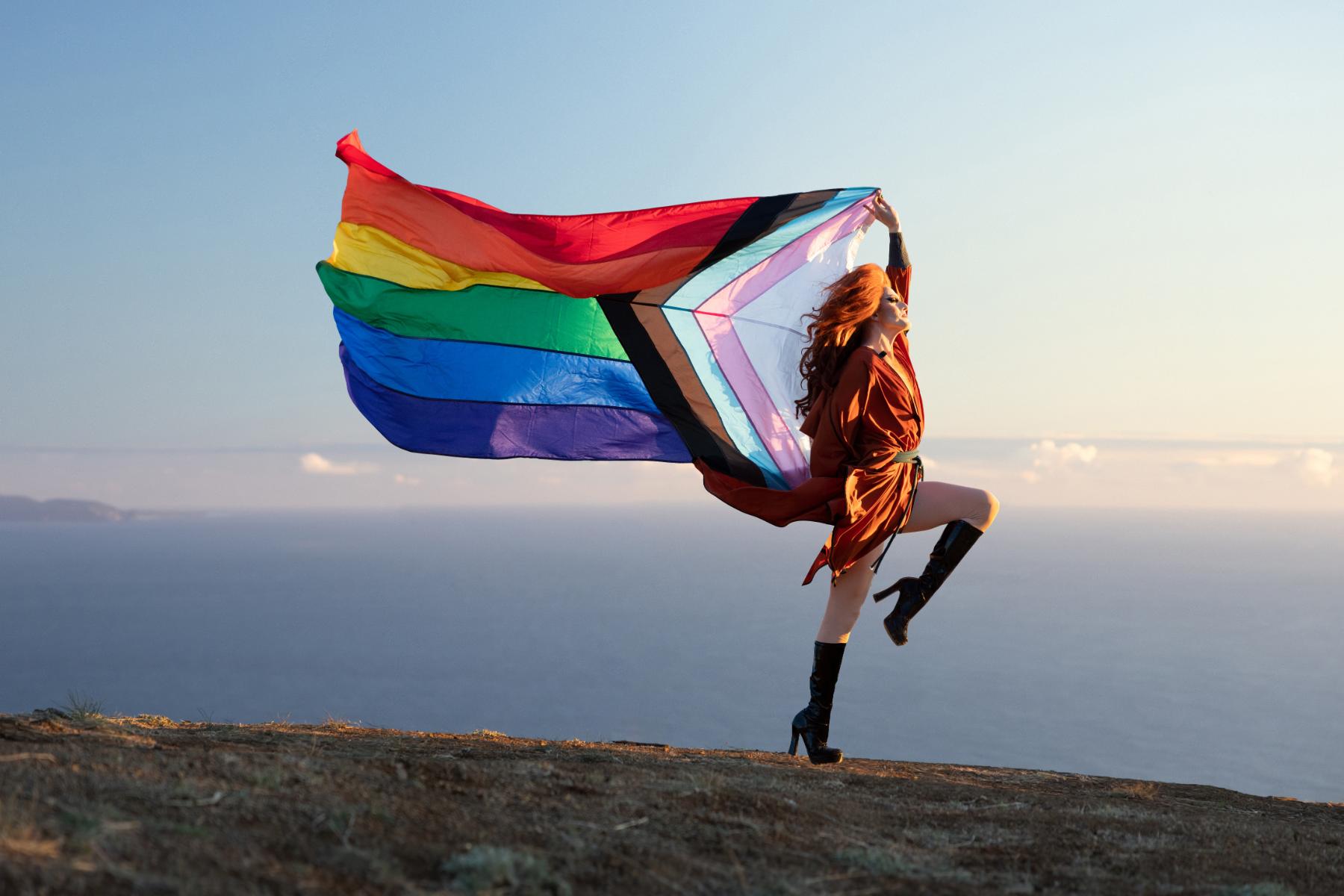 Pattie Gonia holds a Pride Progress Flag.