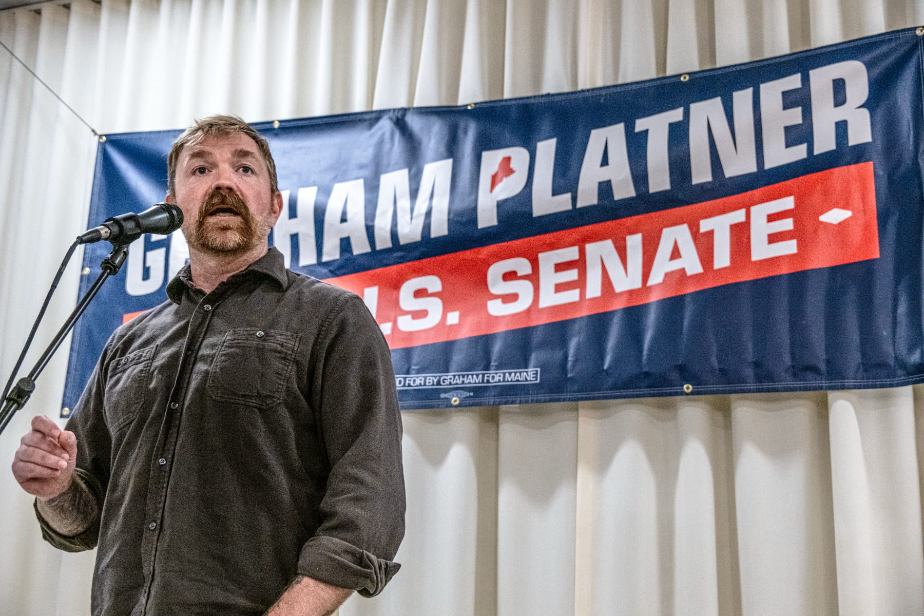 U.S. Senate candidate Graham Platner speaks in front of a sign with his name on it