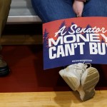 A supporter displays a red and blue sign that reads 'A Senator Money Can't Buy', at the Primary Election event for Democratic U.S. Senate candidate Graham Platner on June 9, 2026 in Blue Hill, Maine.