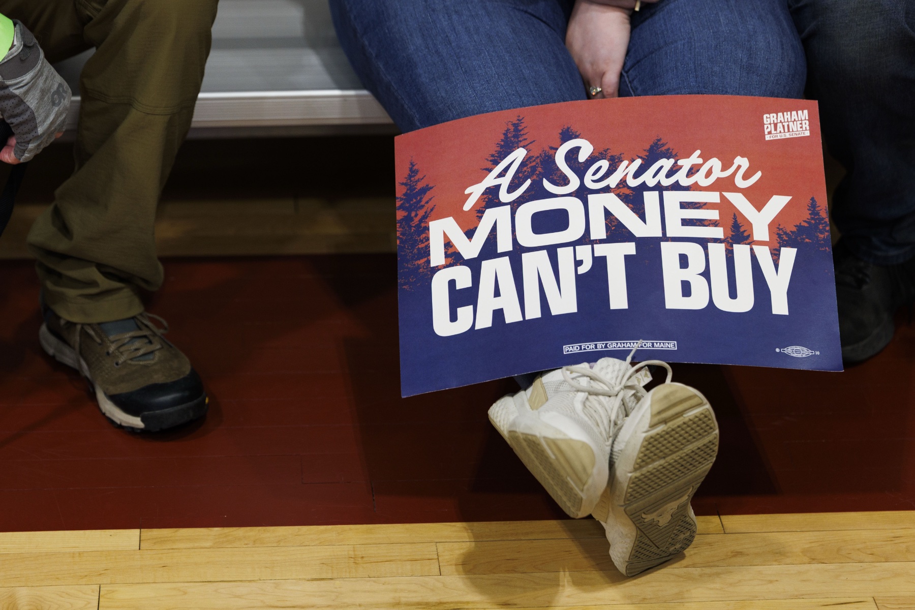 A supporter displays a red and blue sign that reads 'A Senator Money Can't Buy', at the Primary Election event for Democratic U.S. Senate candidate Graham Platner on June 9, 2026 in Blue Hill, Maine.