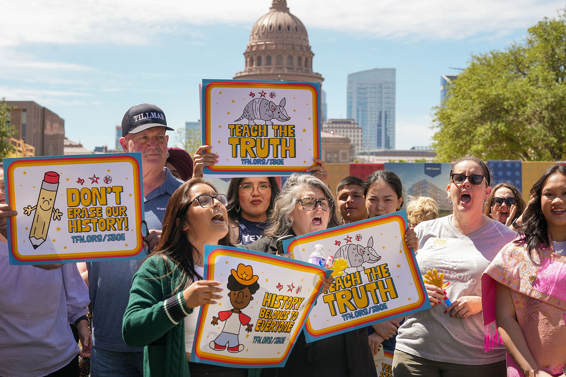 People hold signs that read "Teach the Truth" and "Don't Erase Our History" during a rally on the Capitol Mall outside the Barbara Jordan State Office Building.