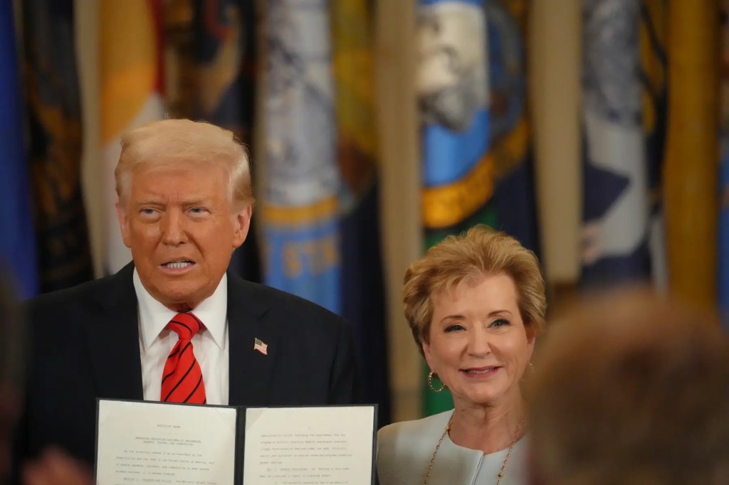 President Donald Trump stands next to Education Secretary Linda McMahon after signing an executive order.