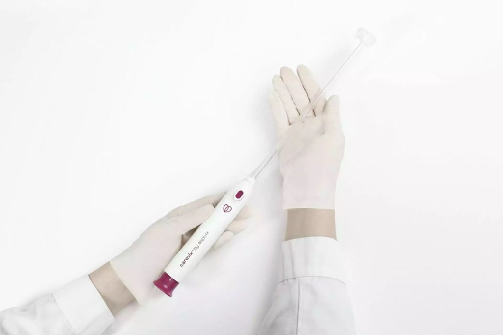 A gloved person holds a Carevix device against a white background. The device has a slim wand with a small suction cup at the end.