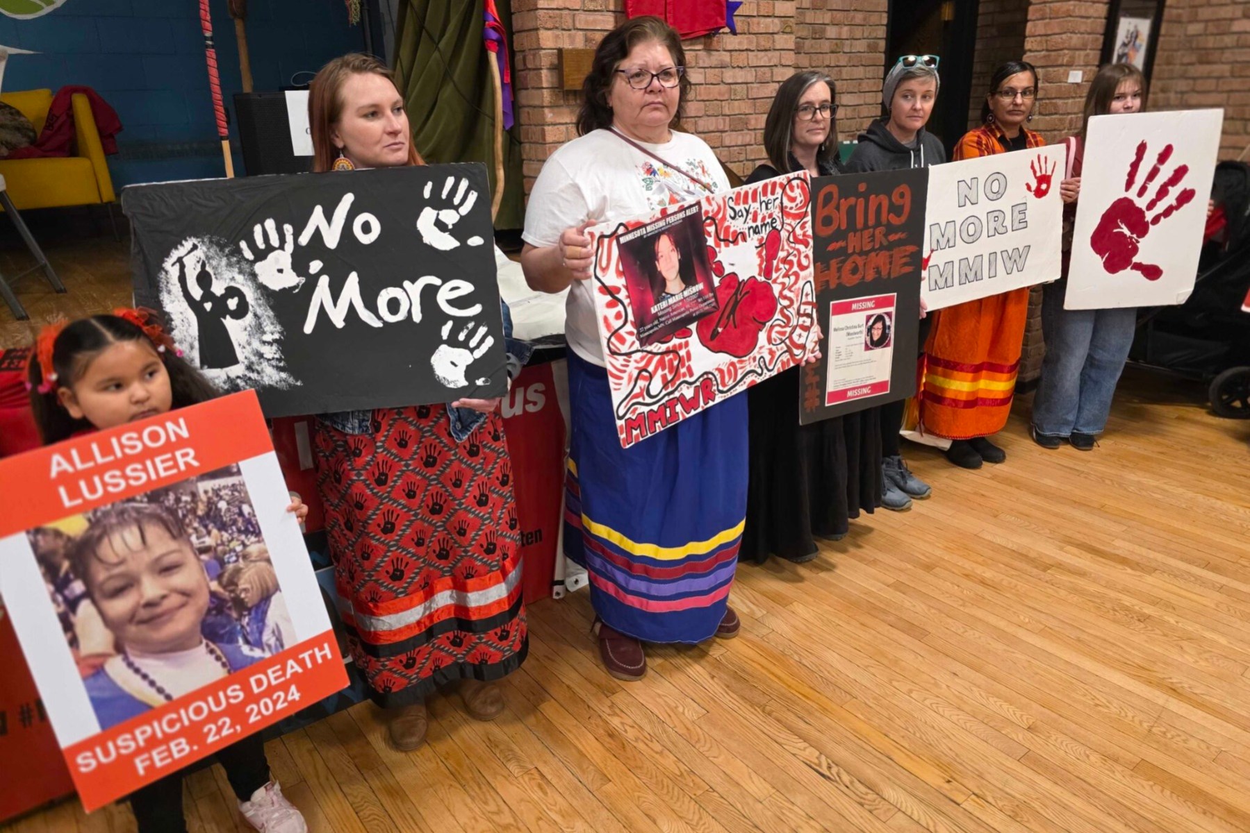 A line of people stand holding signs about missing and murdered Indigenous women.