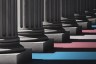 Graphic illustration of dark columns receding into the background, with layered blue, pink and white bands of the transgender pride flag cutting across the shadows of the columns.