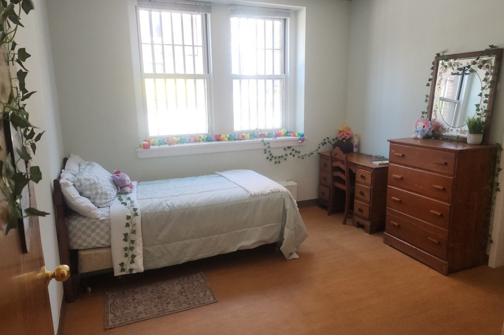 A bedroom with a small bed, dresser, desk and chair.