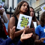 People hold sign of support written in Haitian Creole that translates to 