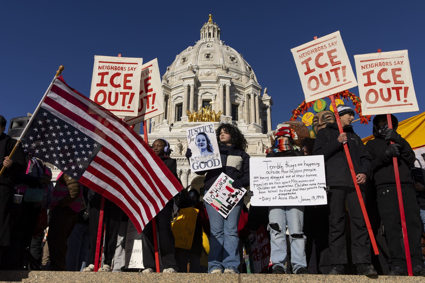 Anti-ICE Protestors wave flags and signs outside a Minneapolis government building.