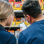 Two people look at a school supply list on a phone while shopping.