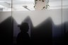 A woman is reflected in silhouette against a window background, maintaining her visual anonymity.