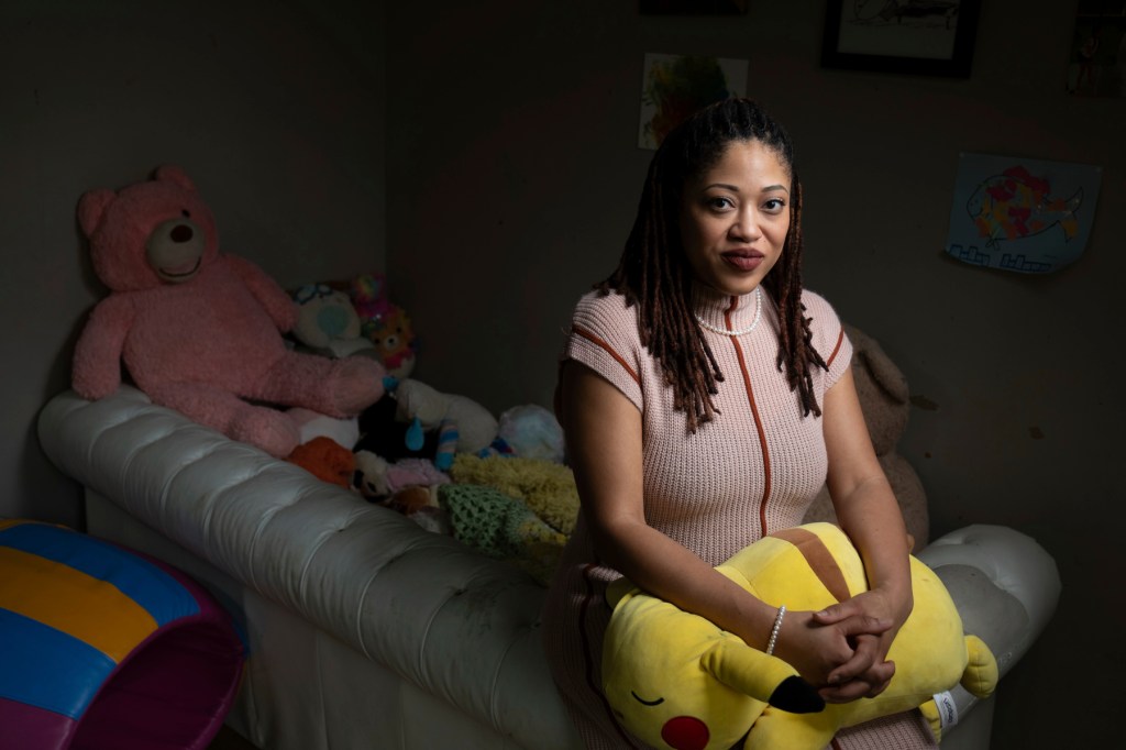 A woman sits on a sofa in a room full of stuffed animals.