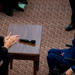 Two men look at each other across a table.