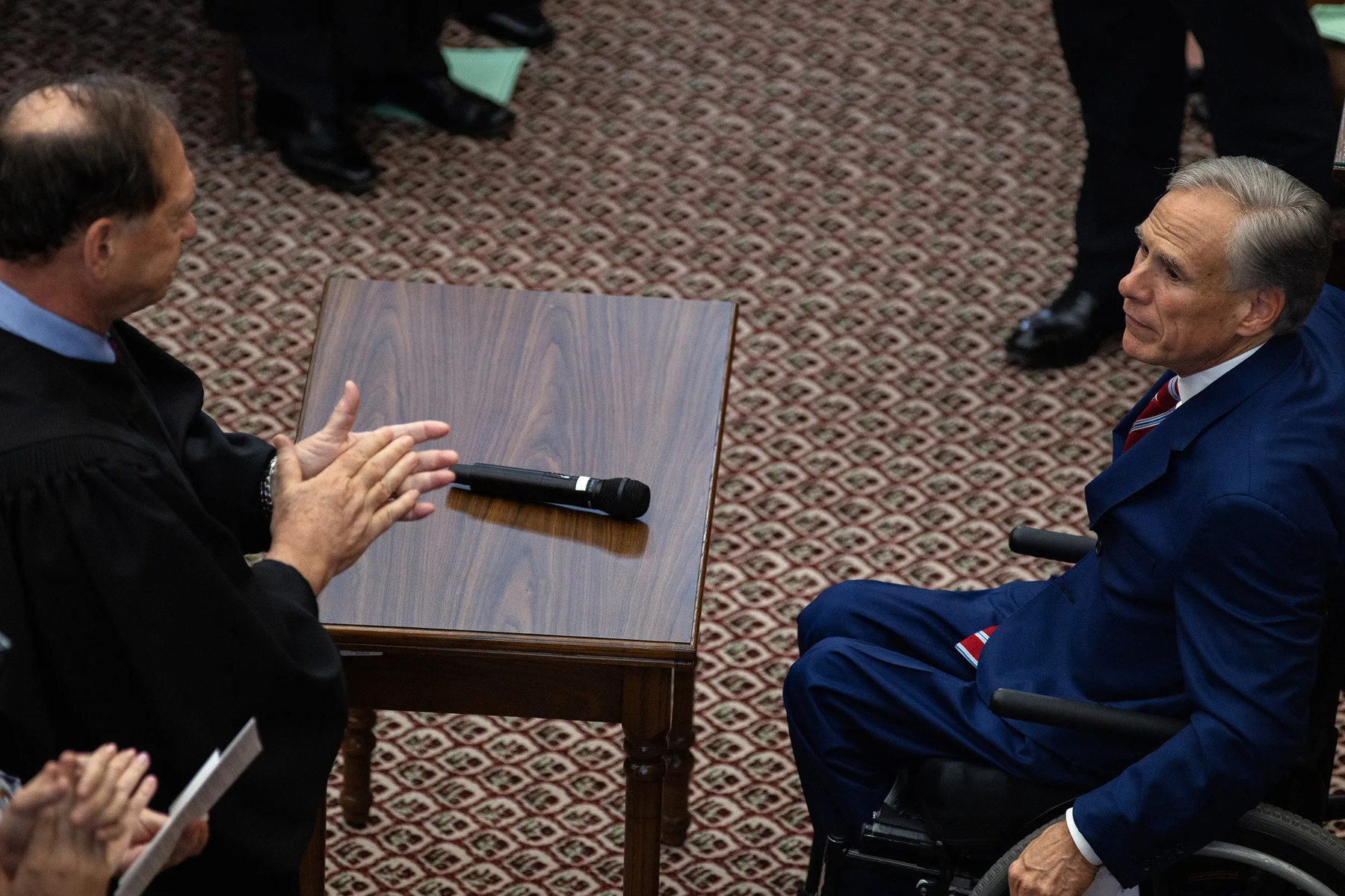 Two men look at each other across a table.