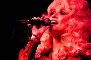 A closeup on Dolly Parton singing with a mic in her hand.