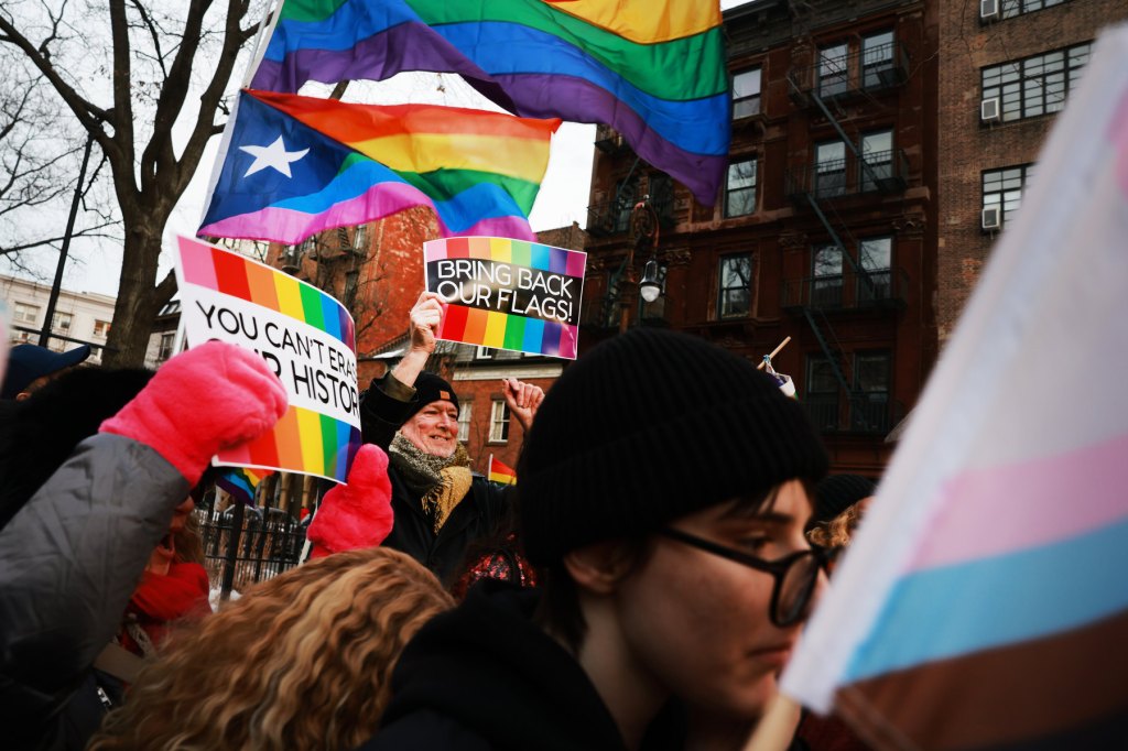 People carrying Pride flags and signs.