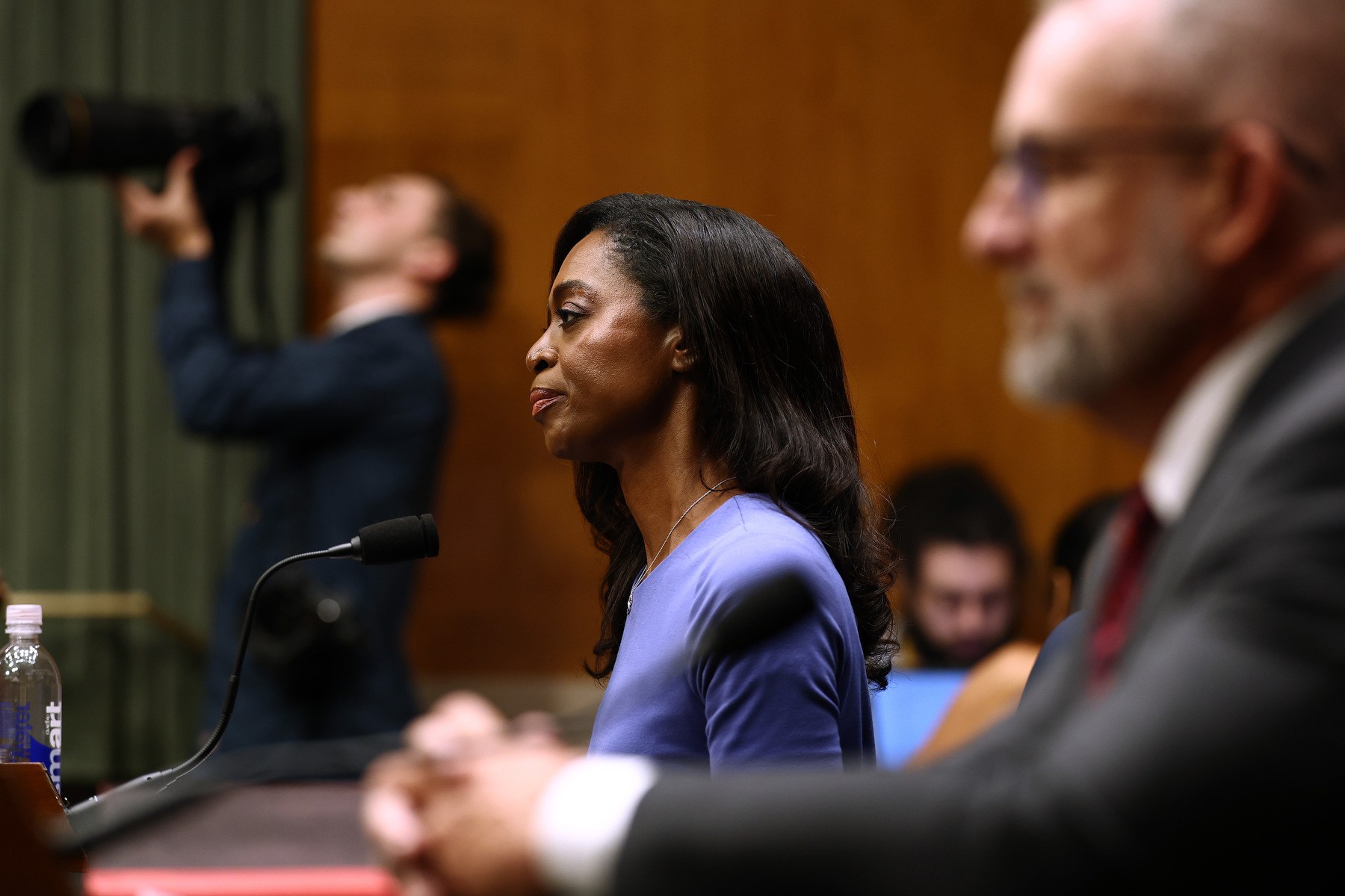 Schwartz sitting at a desk surrounded by white men in the foreground and background.
