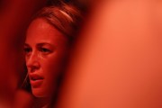 Sophie Cunningham is seen in close-up through a blurred foreground, her face lit in red-orange light.