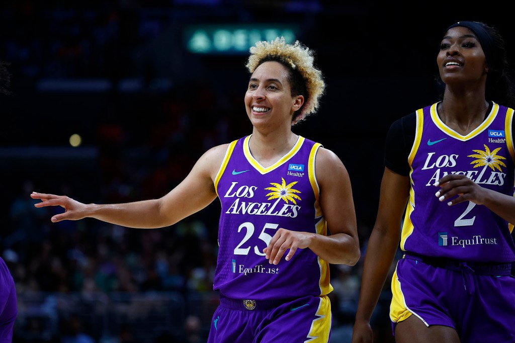 Two Los Angeles basketball players in purple uniforms walk on the court.