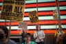 Protesters hold signs calling for the abolition of ICE and immigrant rights during a demonstration in front of a brightly lit display.