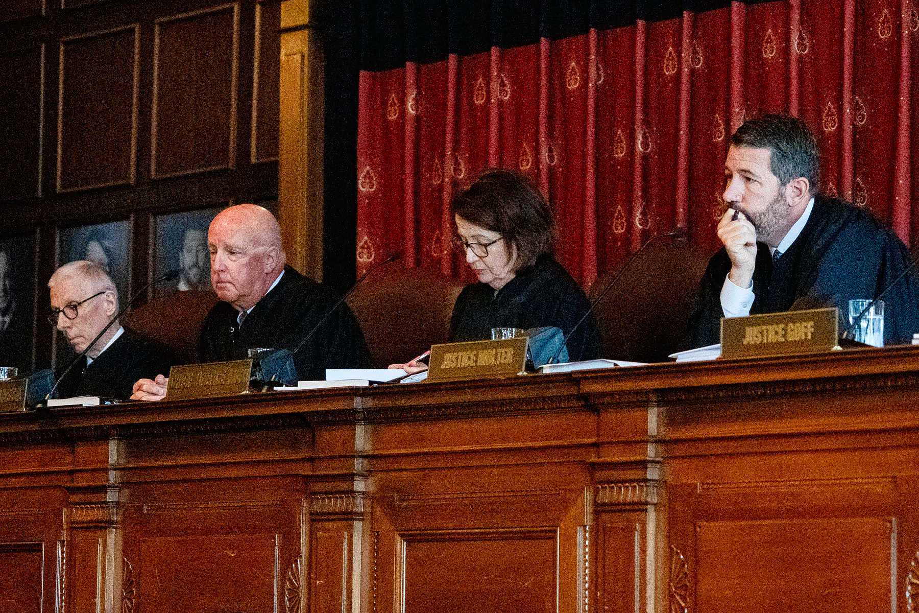 Judges listen to the legal proceedings in a courtroom from above.