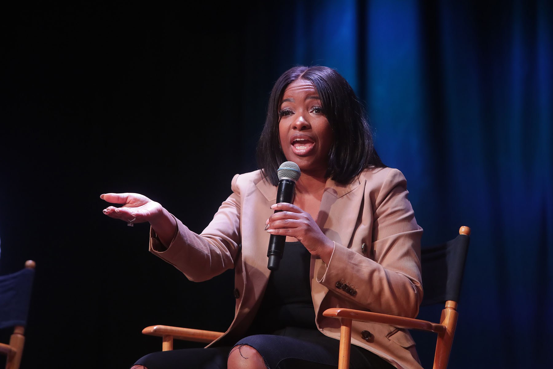 Rep. Jasmine Crockett speaks on stage while holding a microphone during an event in Phoenix, Arizona
