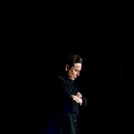 A medium shot of Elon Musk alone and surrounded by darkness.