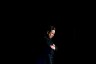 A medium shot of Elon Musk alone and surrounded by darkness.