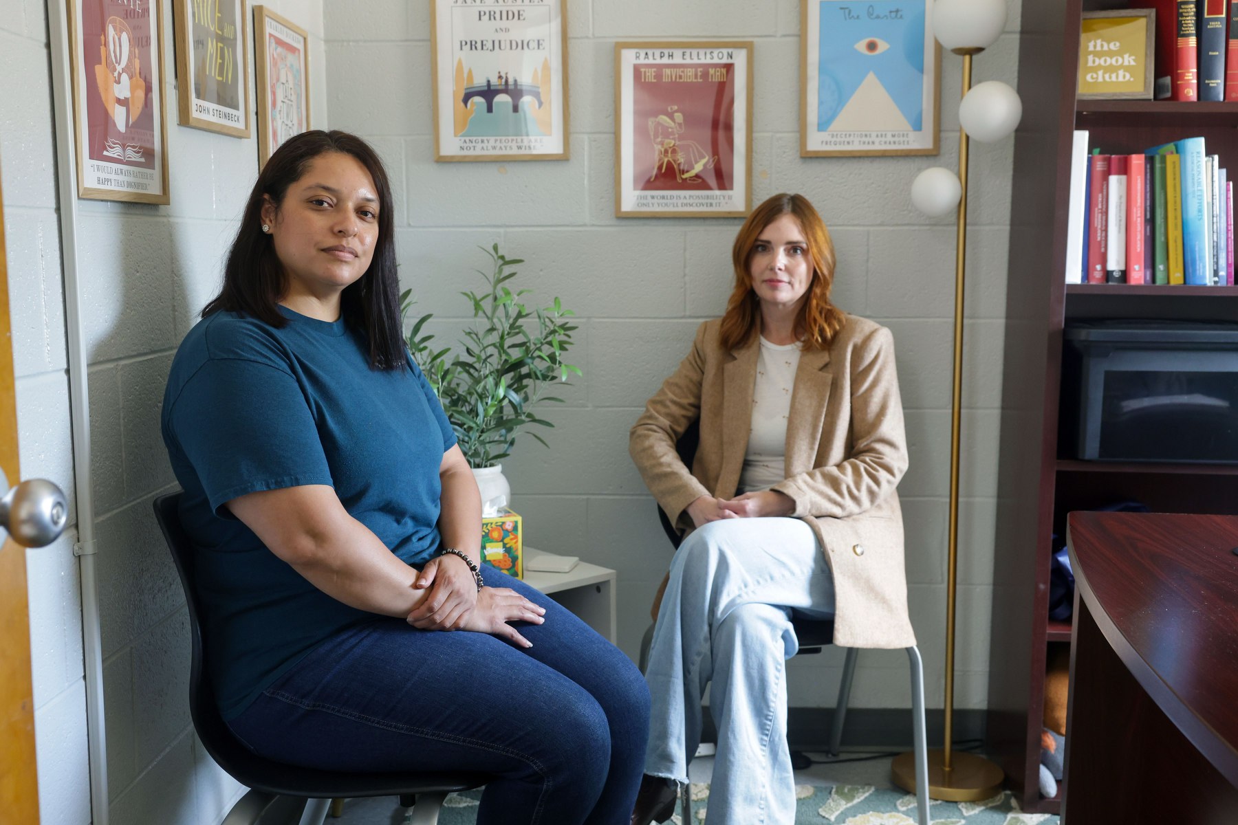 Two people sit in chairs looking at the camera.