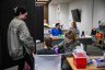 A nurse administers a vaccine to a child while others look on in the room.