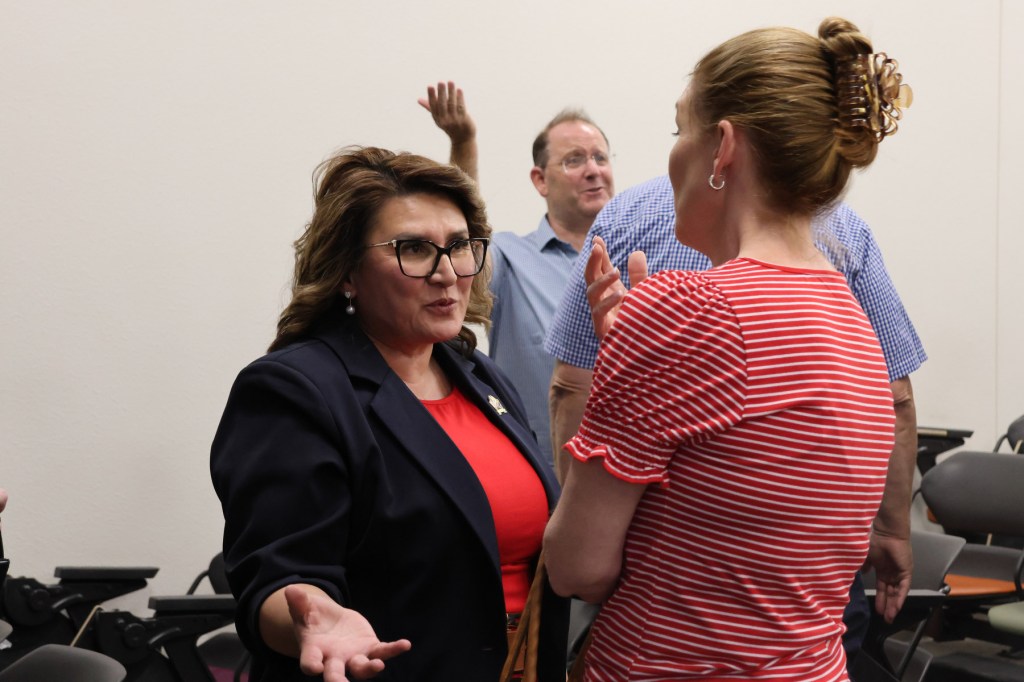 Mendoza gestures while speaking to another woman as others gesticulate in the background.