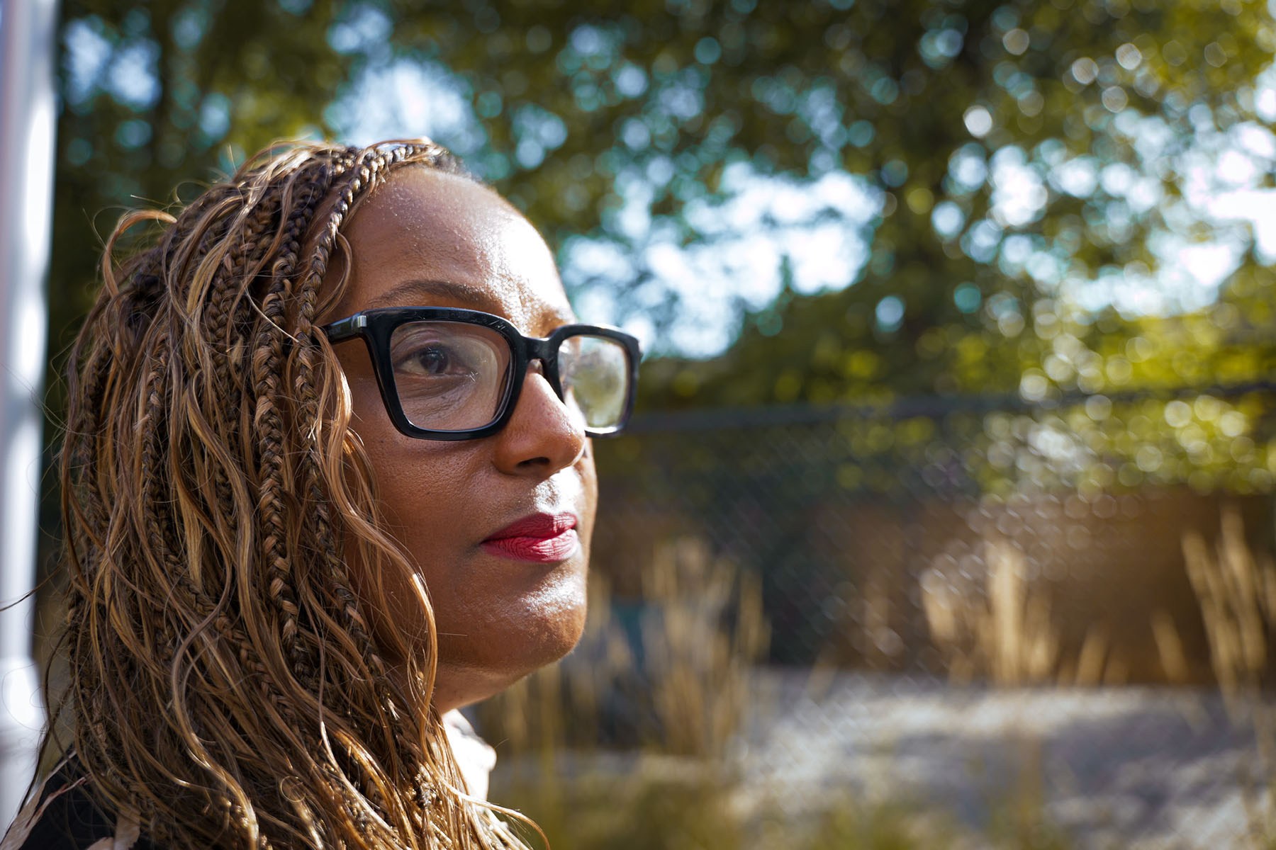 Darnese Foster with braided hair and black-framed glasses looking into the distance outdoors.