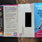 An unfolded brochure titled “Texas Trans & LGBTQ+ Student Resource Guide” lies on a wooden surface. The blue and pink cover features an illustration of two clasped hands and the words “You are not alone.”