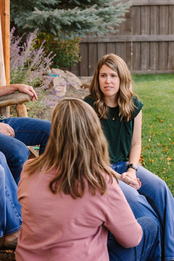Abby talks with family members while seated in the backyard.