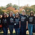 Six women stand together outdoors wearing black Cait Conley campaign shirts that read, 