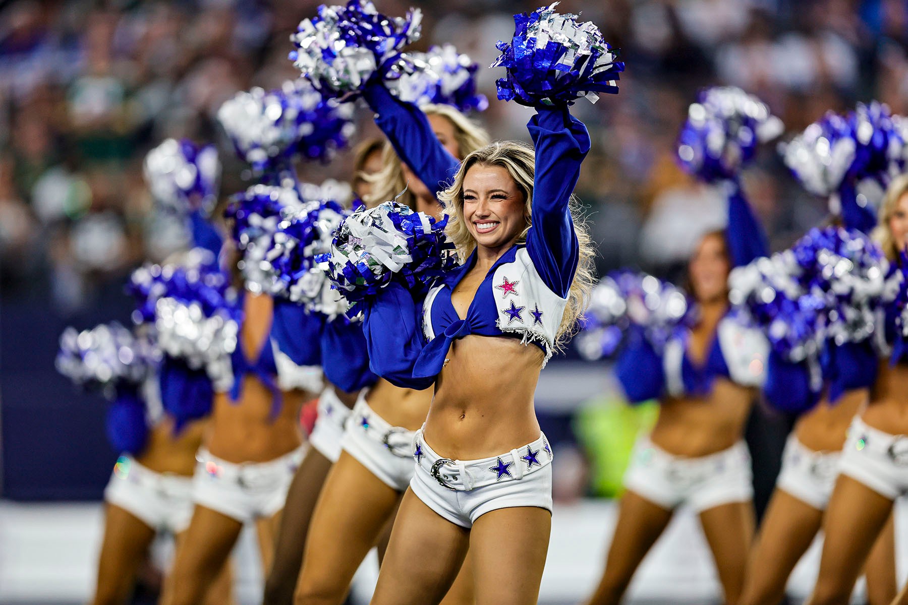 Dressed in blue and white uniforms, the Dallas Cowboys Cheerleaders perform during a game.