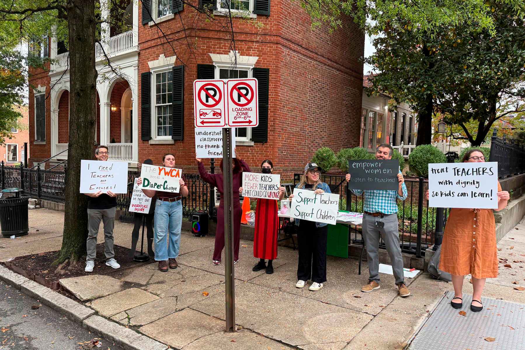 Several people hold protest signs on a street.