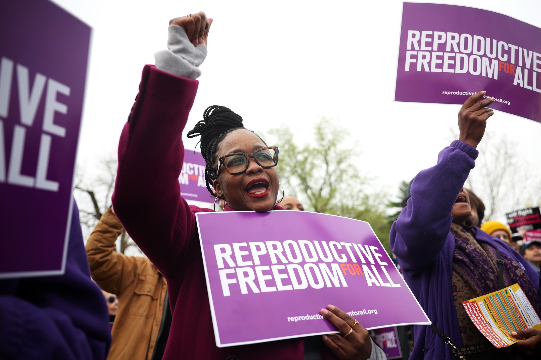 A protestor raises her fist while holding a sign for reproductive rights at a protest.