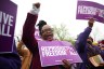 A protestor raises her fist while holding a sign for reproductive rights at a protest.