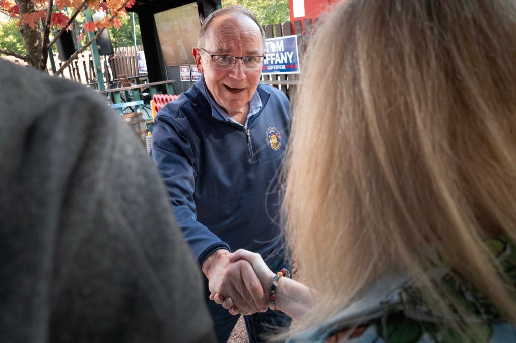 Tiffany shakes hands with two people during a campaign stop.