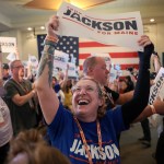 A laughing woman hoists a sign for Jackson during a campaign event.