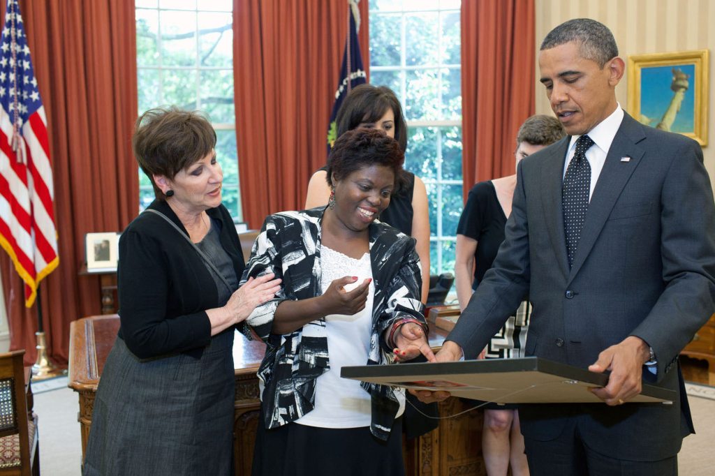 Obama and several other people look at a painting by Lois Curtis.