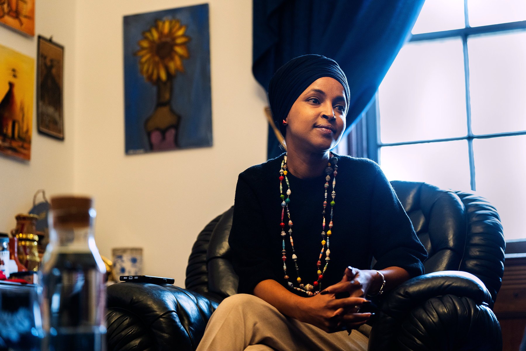 A portrait of Omar sitting on a chair in an office.