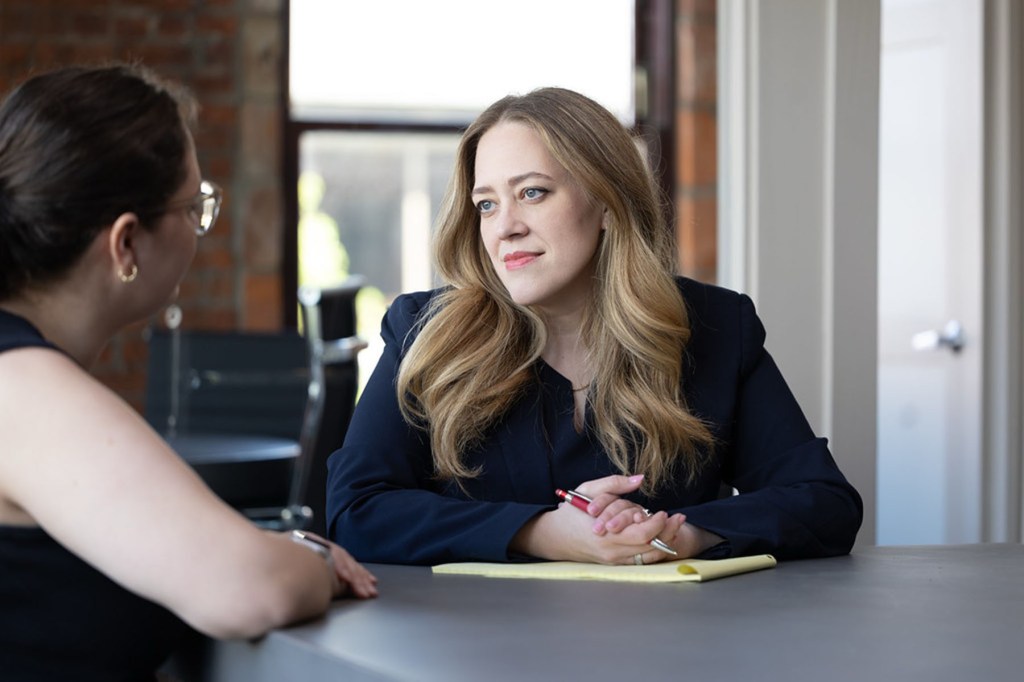 A portrait of Hines seated at a table speaking to another woman.