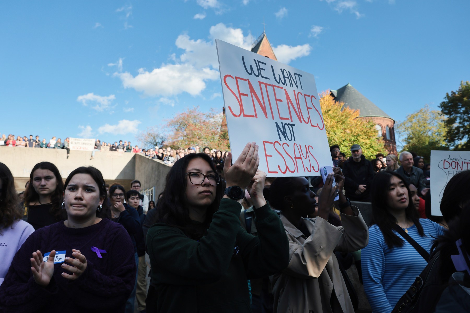 A group of students gather and carry signs in protest.