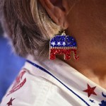Close-up of a woman's red, white and blue glittery elephant earring, symbolizing the Republican Party, and a white shirt decorated with patriotic stars and blue trim.